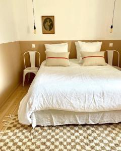 a bedroom with a large white bed with two chairs at L’appartement 39 in Lons-le-Saunier