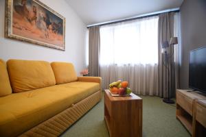 ein Wohnzimmer mit einem gelben Sofa und einem TV in der Unterkunft Apartmani Čarolija in Lučani
