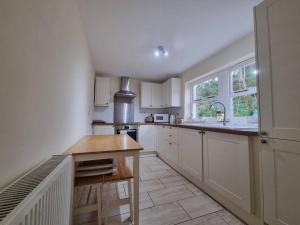Una cocina con gabinetes blancos y una mesa de madera. en Historic cottage next to loch lomond Luss, en Alexandria