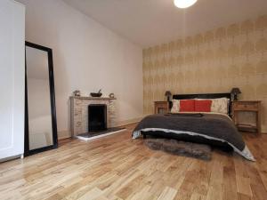 1 dormitorio con cama, chimenea y espejo en Historic cottage next to loch lomond Luss, en Alexandria