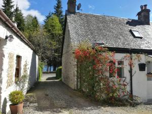 Una casa blanca con flores a un lado. en Historic cottage next to loch lomond Luss en Alexandria