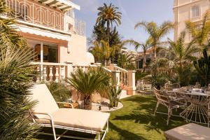 patio z krzesłami, stołami i palmami w obiekcie Maison Carla Rosa Cannes w Cannes