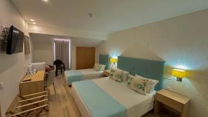 Habitación de hotel con 2 camas y escritorio en Sea Garden Peniche, en Peniche
