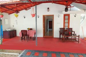 Habitación con suelo rojo, mesa y sillas en Marari La Rose Beach Homestay, en Mararikulam