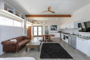 a living room with a brown couch and a kitchen at CLIFFSIDE: BONDI BEACH in Sydney