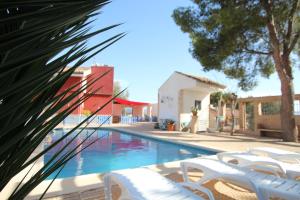 einen Pool mit weißen Stühlen neben einem Gebäude in der Unterkunft Casa La Noria by Rental Olé in Murcia