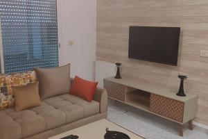 a living room with a couch and a flat screen tv at Cosy and Charming Apartment close to TUNISIA MALL Lac2 Tunis in Tunis