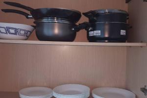 a shelf with pots and pans and plates in a kitchen at Cosy and Charming Apartment close to TUNISIA MALL Lac2 Tunis in Tunis