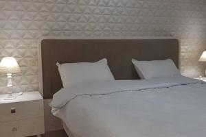 a bedroom with a white bed with two lamps at Cosy and Charming Apartment close to TUNISIA MALL Lac2 Tunis in Tunis