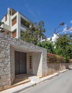 a house with a stone wall and a building at Sea view penthouse in Vari in Vari