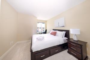 a bedroom with a large white bed with a night stand at Downtown Osprey Condo at Waterscapes in Kelowna