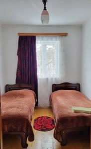 twee bedden in een kamer met een raam en een tapijt bij Guest house Data in Ushguli