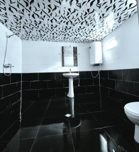 een badkamer met een toilet en zwarte en witte tegels bij Guest house Data in Ushguli