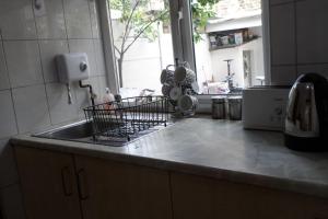 a kitchen sink with a dish rack on the counter at Bubblesbnb, 1 bedroom flat in London