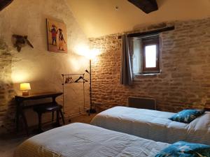een slaapkamer met 2 bedden, een bureau en een raam bij La Vallée Verte in Grandchamp