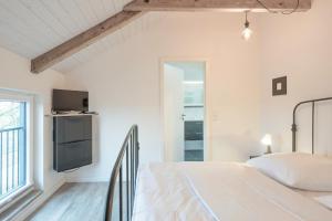 a white bedroom with a bed and a tv at Fofteinbutze dree in Nordstrand