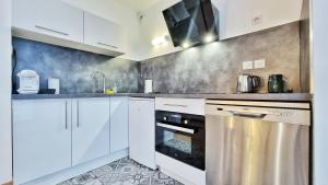 kuchnia z białymi szafkami i piekarnikiem ze stali nierdzewnej w obiekcie Le SMART - Parking - Terrasse - Wifi - Mulhouse - Relax BNB w mieście Pfastatt