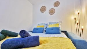 łóżko z niebiesko-żółtymi kocami i poduszkami w obiekcie Le SMART - Parking - Terrasse - Wifi - Mulhouse - Relax BNB w mieście Pfastatt