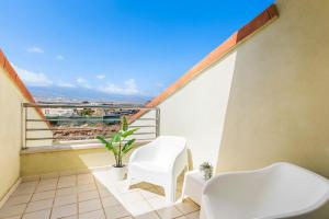 a balcony with two white chairs and a plant at MEDANO4YOU Los Patios Family and Sports Home in El Médano