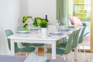 a white table with green chairs and wine glasses at MEDANO4YOU Los Patios Family and Sports Home in El Médano