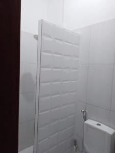 a white tiled bathroom with a toilet and a shower at Centric Alter a 600m da praia in Alter do Chao