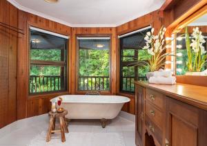 a bathroom with a white tub and windows at The Forest Buré - Fijian Hinterland Retreat in Ninderry