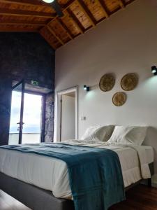 a bedroom with a large bed and a window at Quinta do Caminho da Igreja TER-Casas de Campo in Velas