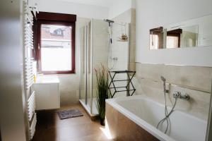 a bathroom with a tub and a sink and a mirror at Jenapartments Design Loft, Damenviertel im Stadtzentrum in Jena