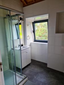 a bathroom with a shower and a sink and a window at Quinta do Caminho da Igreja TER-Casas de Campo in Velas