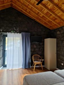 ein Schlafzimmer mit einem Bett, einem Stuhl und einem Fenster in der Unterkunft Quinta do Caminho da Igreja TER-Casas de Campo in Velas