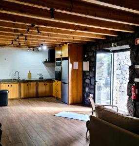 an open kitchen with wooden cabinets and a living room at Quinta do Caminho da Igreja TER-Casas de Campo in Velas