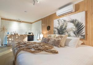 a bedroom with a large white bed with a large picture on the wall at The Forest Buré - Fijian Hinterland Retreat in Ninderry
