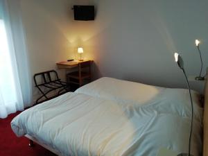 1 dormitorio con 1 cama y escritorio con lámpara en Hôtel Chez Pierre d'Agos, en Agos-Vidalos