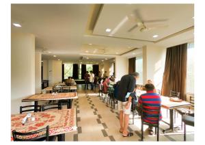a group of people sitting at tables in a restaurant at Hotel Lalit inn in Lonavala