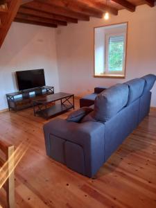 a living room with a blue couch and a tv at Casa Mariñao 1 in Loiba