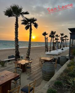 - un coucher de soleil sur la plage avec des tables et des palmiers dans l'établissement Realmonte Casa vacanze Realbeach, à Realmonte