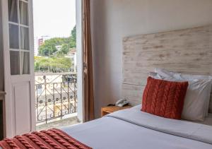 1 dormitorio con 1 cama y vistas a un balcón en Kastel Grão Pará en Petrópolis