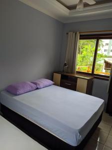 ein Schlafzimmer mit einem Bett mit lila Kissen und einem Fenster in der Unterkunft iUP HOUSE Hostel in Blumenau