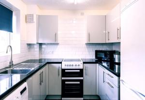 a kitchen with white cabinets and a stove top oven at New 2 Bedroom House NR Parkway Station - Free Parking in Bristol
