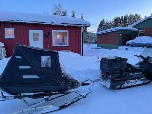 ein Schneemobil, das vor einem roten Haus parkt in der Unterkunft Mitt i Sveg, Färjegatan 6 in Sveg