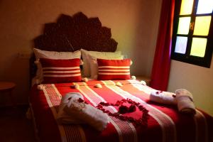 een slaapkamer met een rood en wit bed met kussens bij Riad Bab Nour in Marrakesh