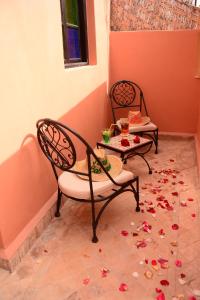 twee stoelen en een tafel met bloemen op de vloer bij Riad Bab Nour in Marrakesh