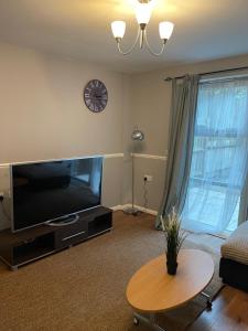 a living room with a flat screen tv and a table at Southend Lane Suites in Forest Hill