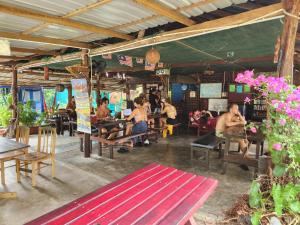 um grupo de pessoas sentadas em mesas em um restaurante em Gecko Guesthouse em Pantai Cenang