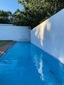 a blue swimming pool with a white wall at Casa do Carvalhal - Quinta do Soldado in Alquerubim