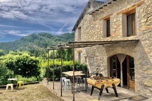 une maison en pierre avec une table et des chaises sur une terrasse dans l'établissement Gîte d'étape Bastide Petra Castellana Verdon, à Castellane