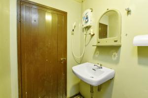 a bathroom with a sink and a wooden door at OYO 90627 Pulau Ketam Inn in Klang