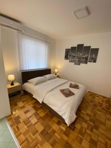 a bedroom with a large white bed and a wooden floor at Apartmani Milojić in Soko Banja