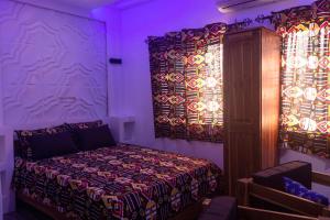 a bedroom with a bed and curtains with purple lights at Les perles du bonheur Nyékonakpoé in Lomé