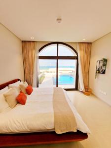 a bedroom with a large bed with a large window at Jebel Sifah Suites in As Sīfah